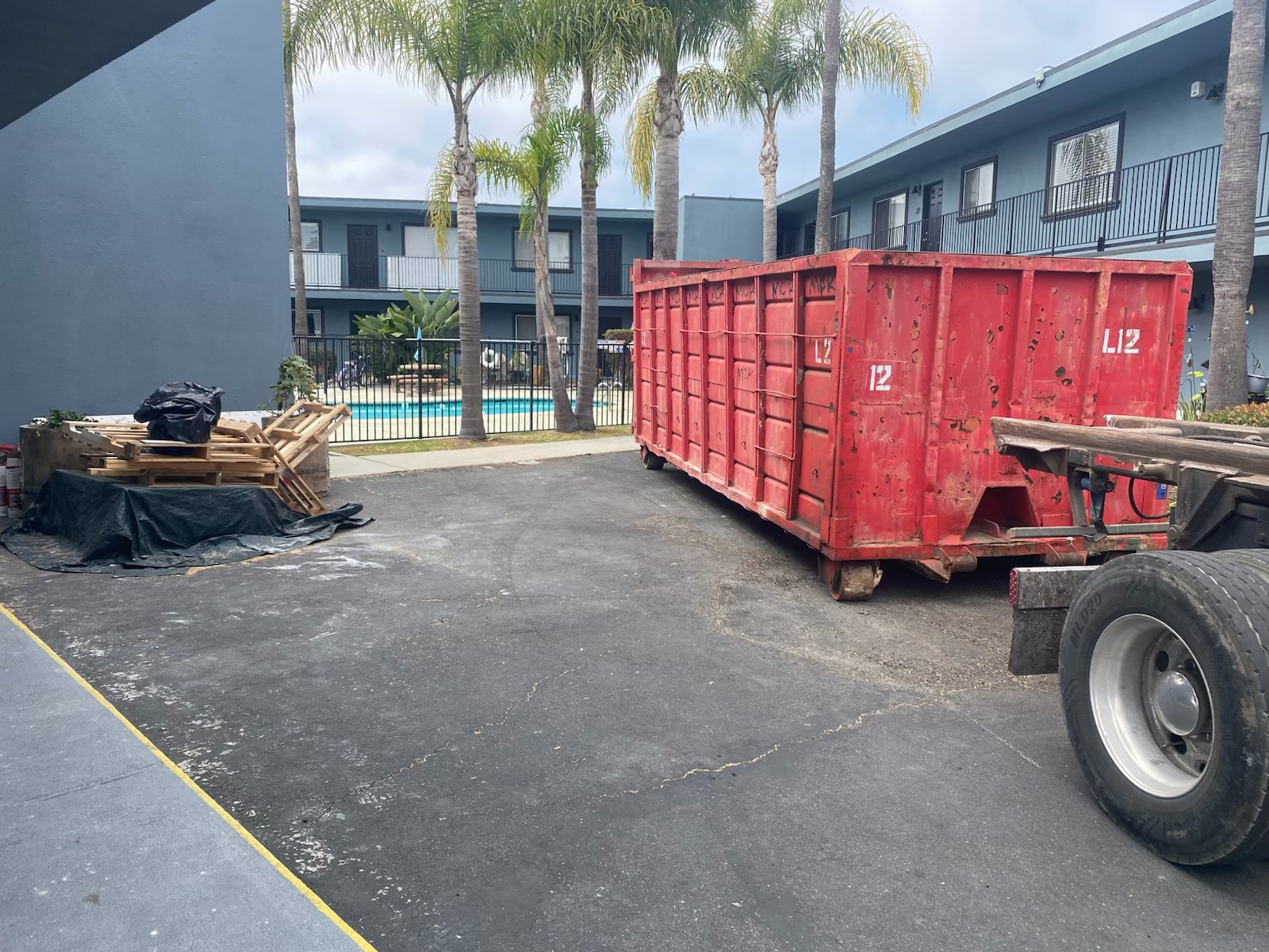 Red Heverly & Sons roll-off dumpster delivered to a Poway apartment courtyard near the pool