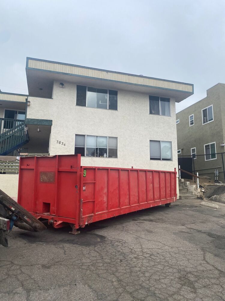 25-yard red roll-off dumpster delivered to a North Park apartment complex driveway for a multi-unit cleanout